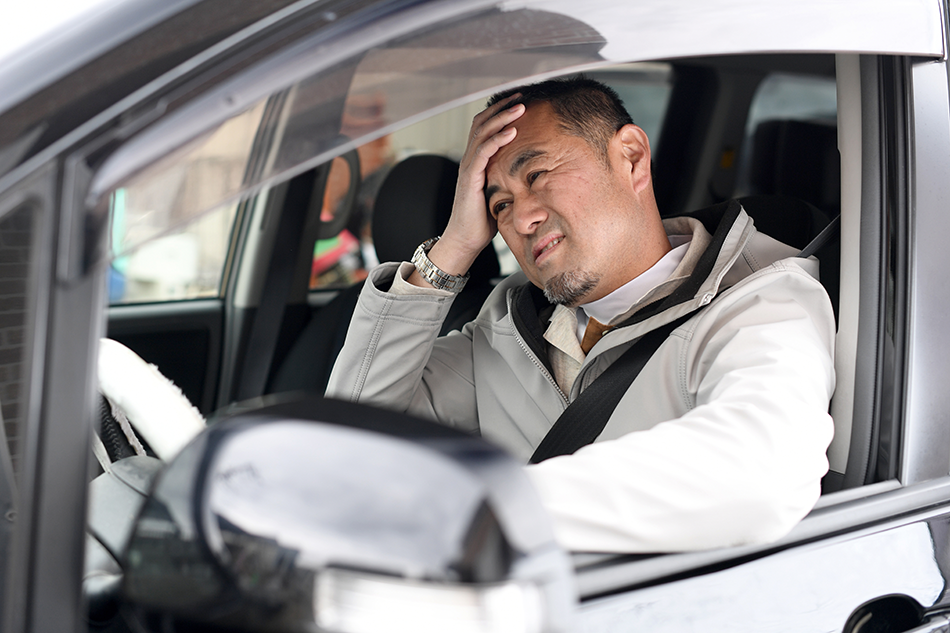 営業車を運転している困った様子の男性
